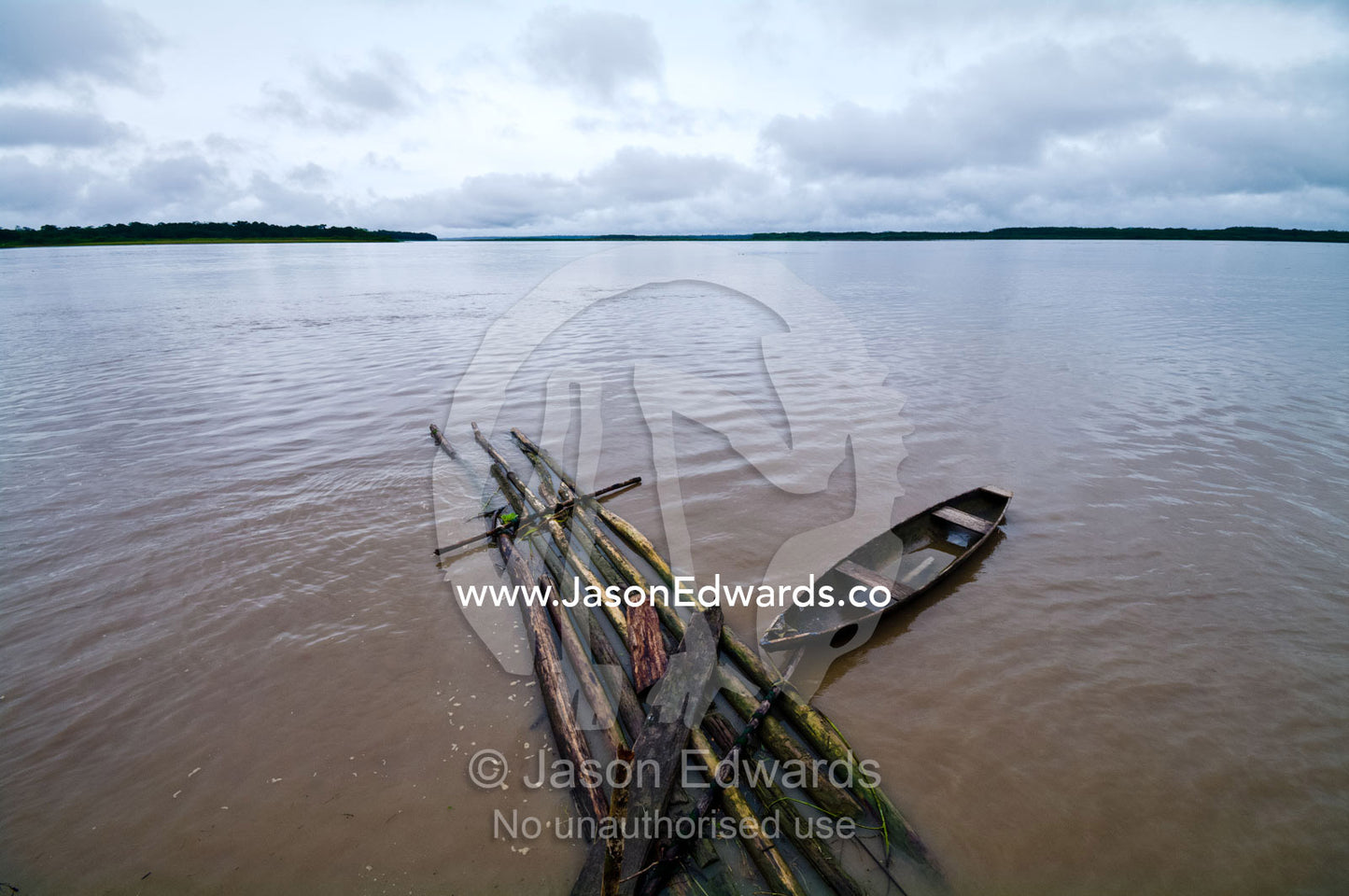 A wooden canoe moored to a pontoon of logs cut from the Amazon rainforest. Pacaya Samiria National Reserve, Reserva Nacional Pacaya Samiria, Amazon River, Maranon River, Ucayali River, Loreto Region, Maynas Province, Amazon Basin, Peru.