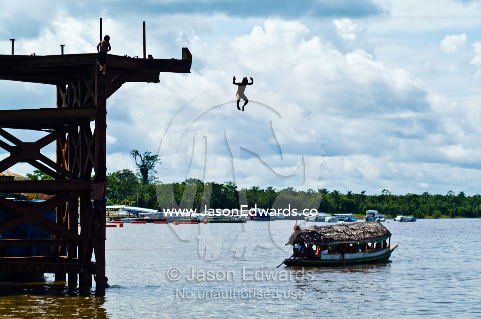 Teenagers leap into a river far below during the dry season when water levels are low. Iquitos, Loreto Region, Maynas Province, Amazon Basin, Peru.