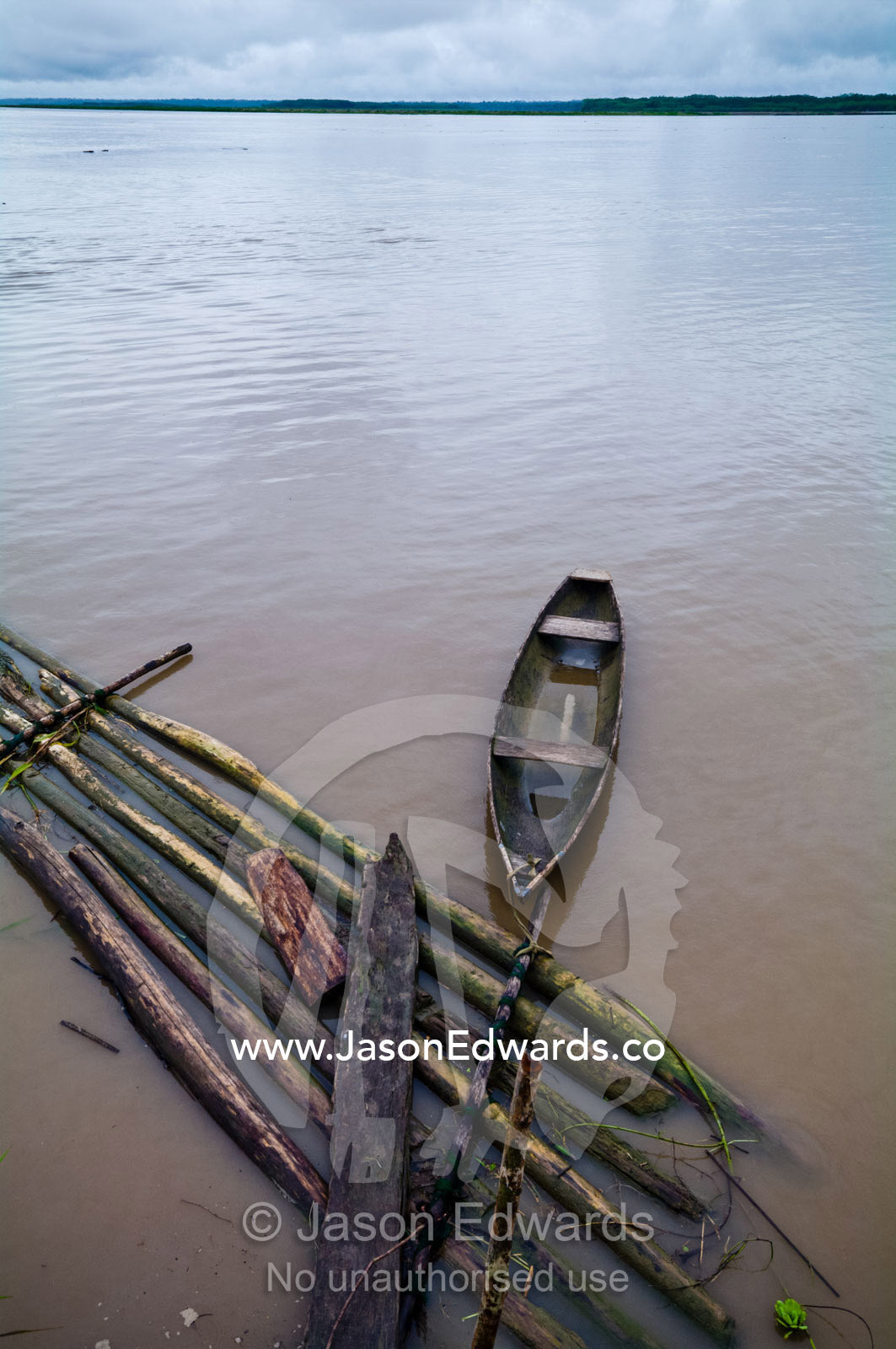 A wooden canoe moored to a pontoon of logs cut from the Amazon rainforest. Pacaya Samiria National Reserve, Reserva Nacional Pacaya Samiria, Amazon River, Maranon River, Ucayali River, Loreto Region, Maynas Province, Amazon Basin, Peru.