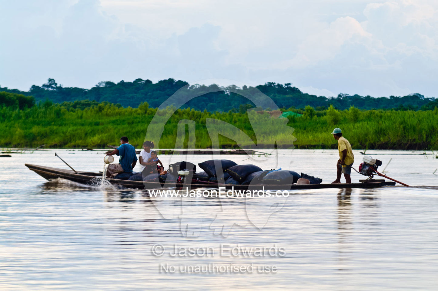 A villager bails water from a heavily laden water taxi carrying goods and a family to market. Pacaya-Samiria National Reserve, Reserva Nacional Pacaya - Samiria, Loreto Region, Maynas Province, Amazon Basin, Peru.