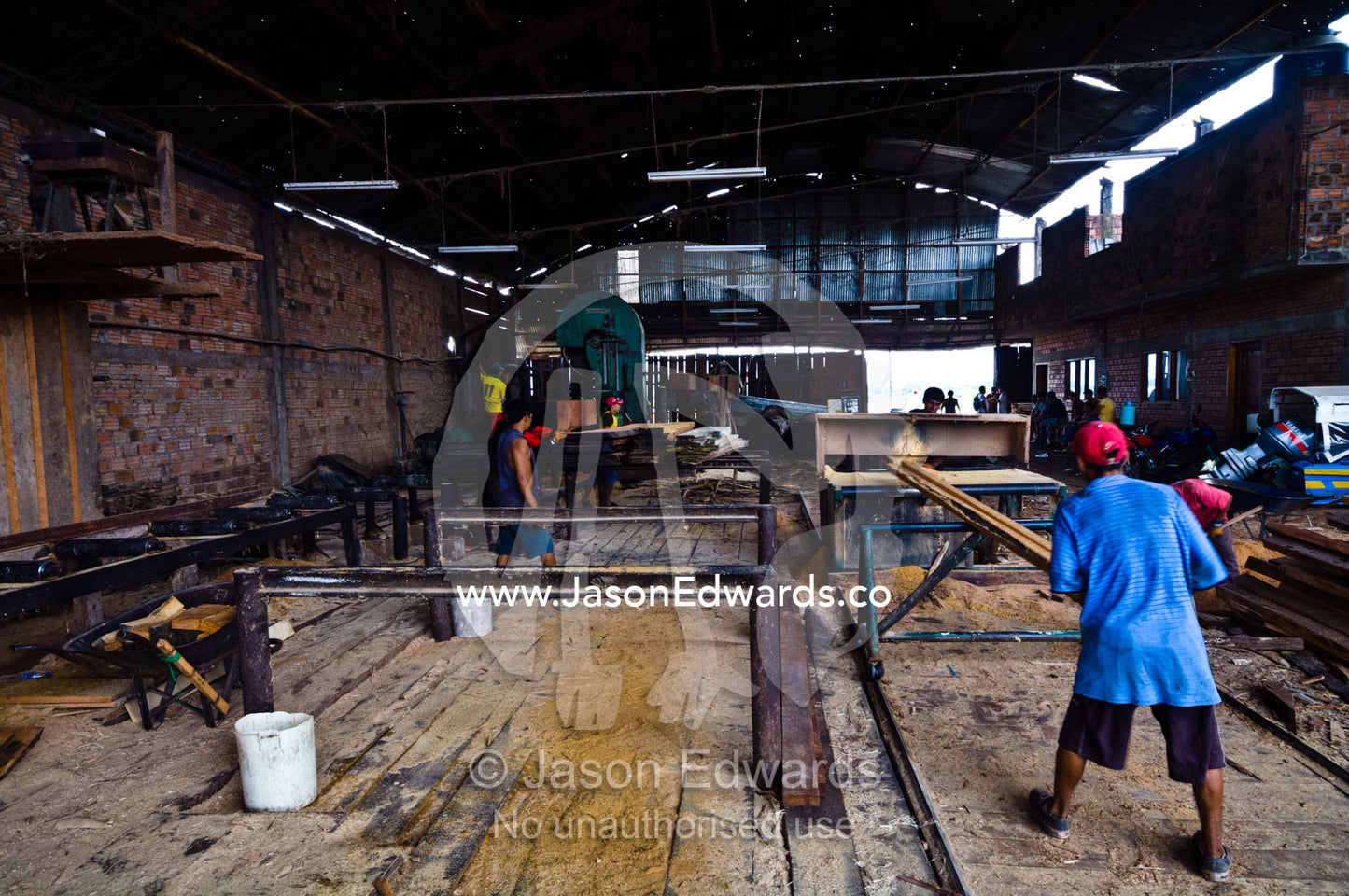Laborers cutting timber planks from rainforest trees in a logging mill. Puerto Masusa, Iquitos, Amazon Basin, Loreto Region, Maynas Province, Peru.