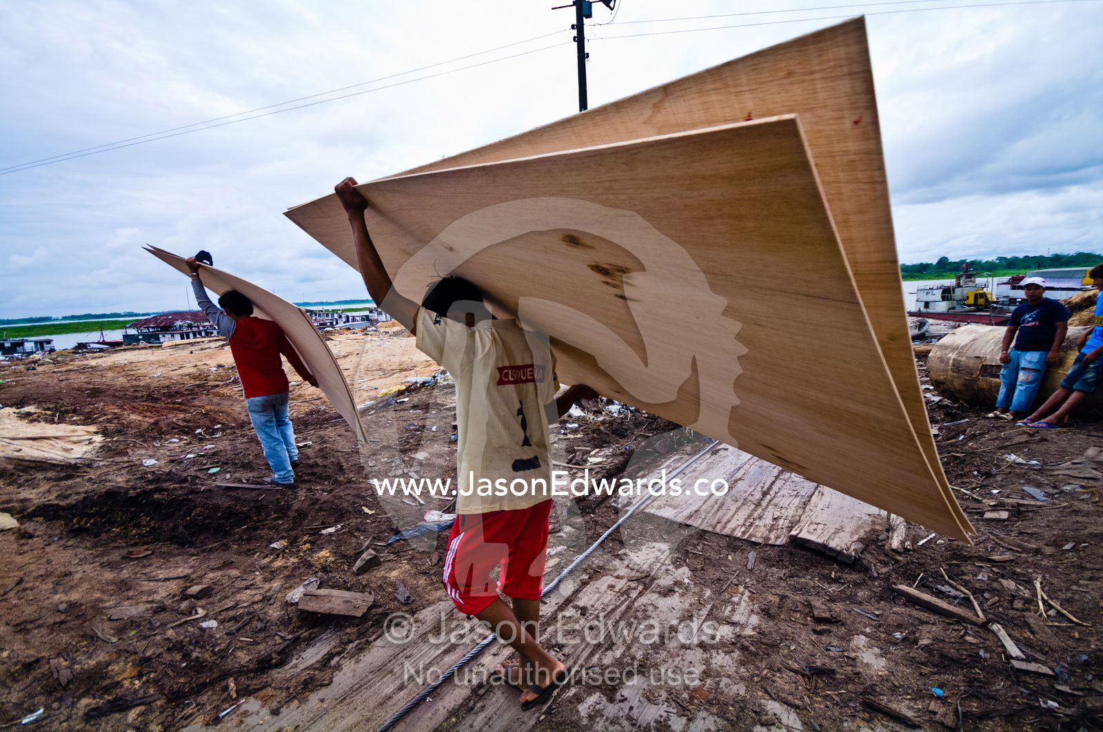 Men carry timber sheets cut from large rainforest trees. Puerto Masusa, Iquitos, Amazon Basin, Loreto Region, Maynas Province, Peru.