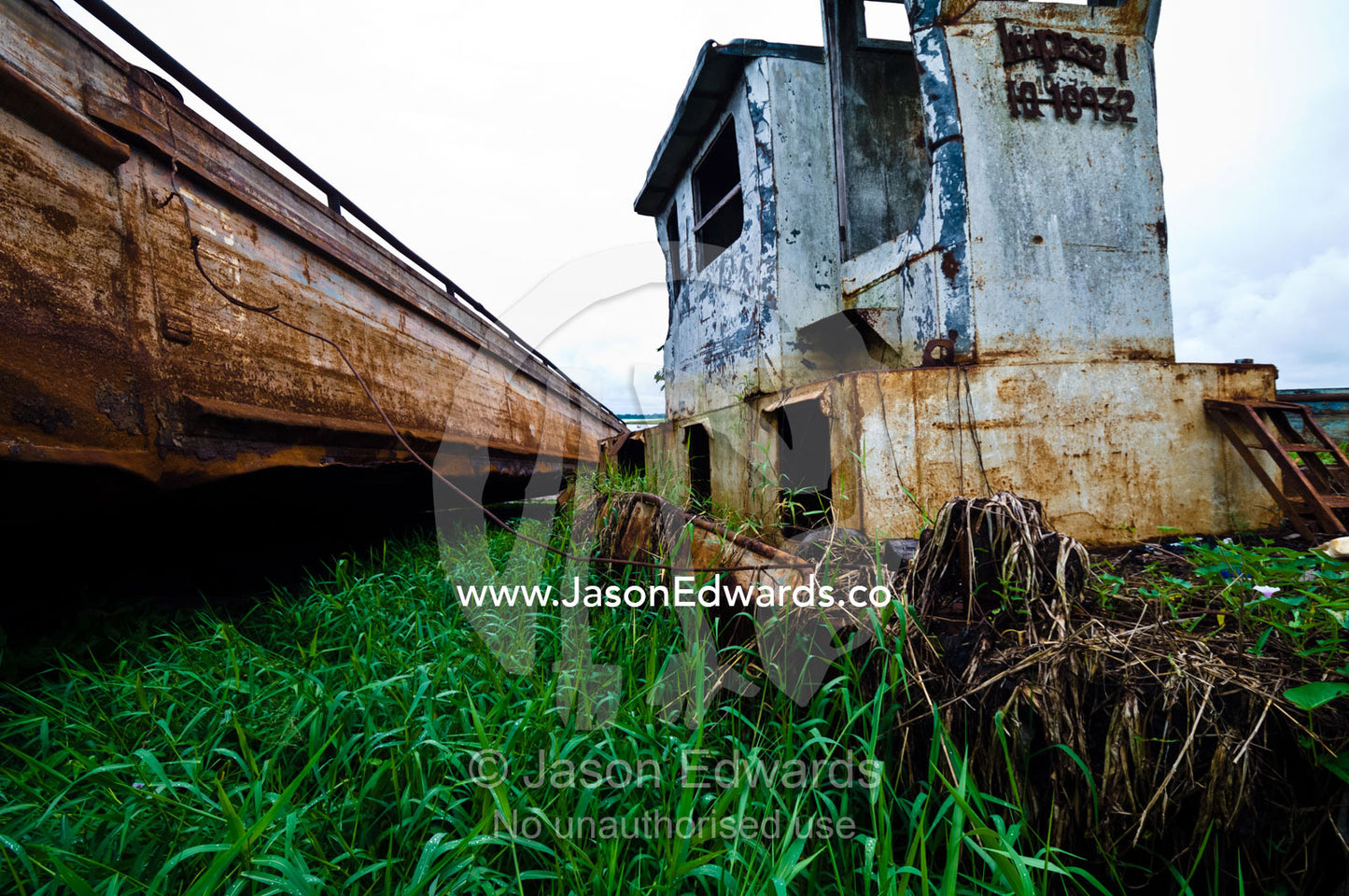 River barges used for transporting timber from logging mills rusting on the shore of a wide estuary. Puerto Masusa, Amazon River, Rio Amazonas, Iquitos, Amazon Basin, Loreto Region, Maynas Province, Peru.