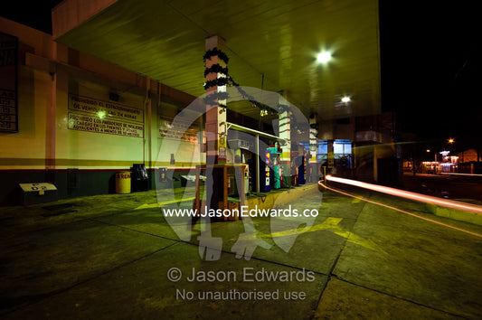 A motorbike auto rickshaw drives out of a petrol station after refuelling at night. Iquitos, Amazon Basin, Loreto Region, Maynas Province, Peru.