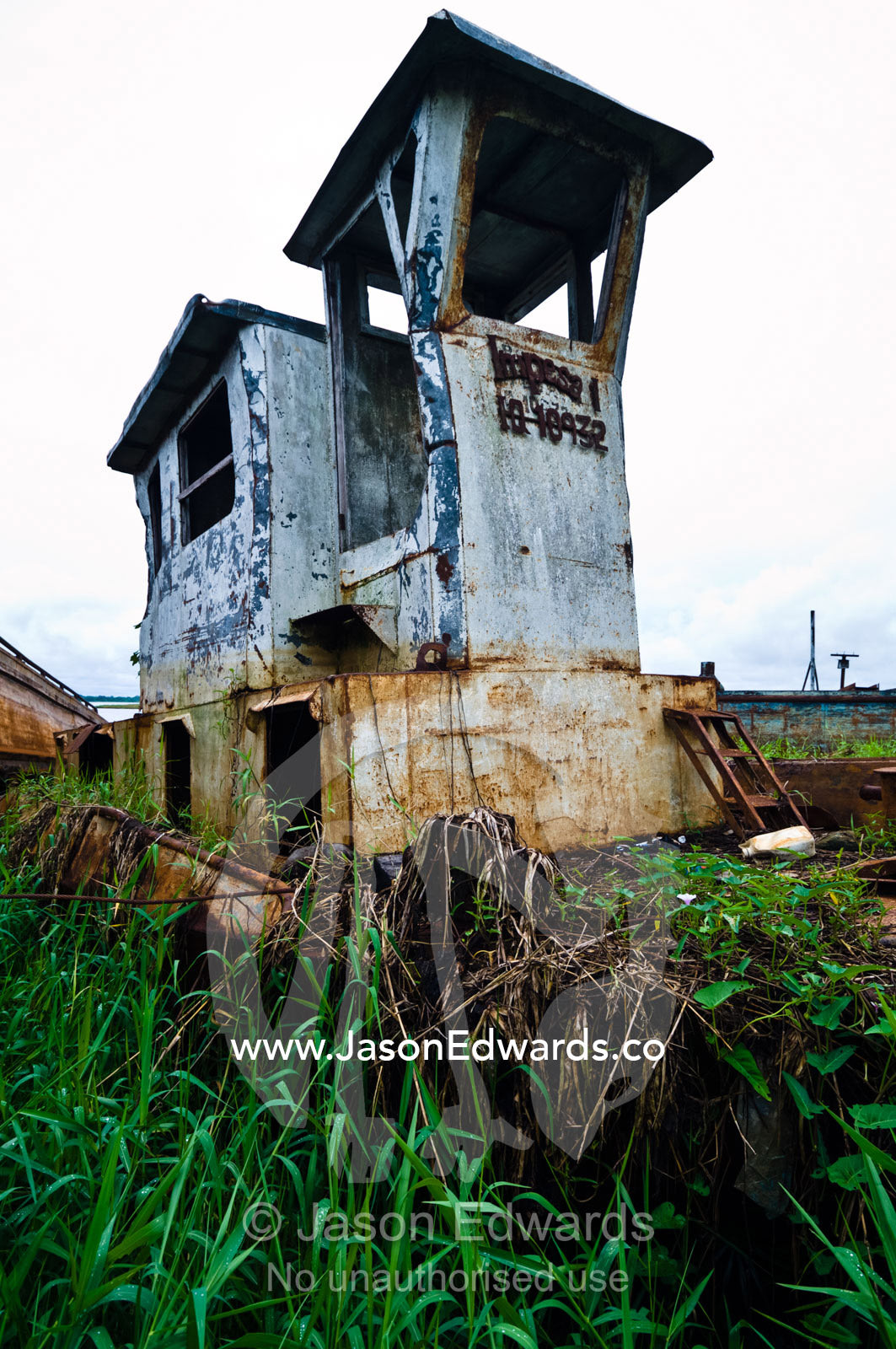 River barges used for transporting timber from logging mills rusting on the shore of a wide estuary. Puerto Masusa, Amazon River, Rio Amazonas,  Iquitos, Amazon Basin, Loreto Region, Maynas Province, Peru.