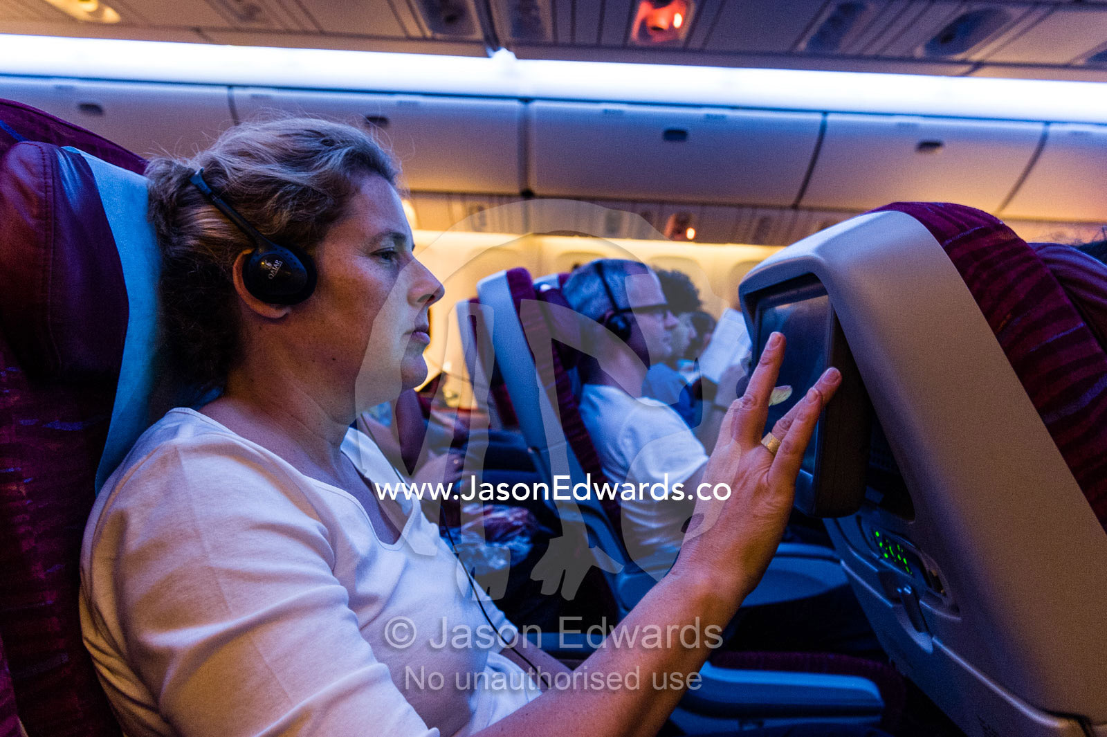 A woman selects a movie to watch on an international flight. Doha, Doha International Airport, Qatar.