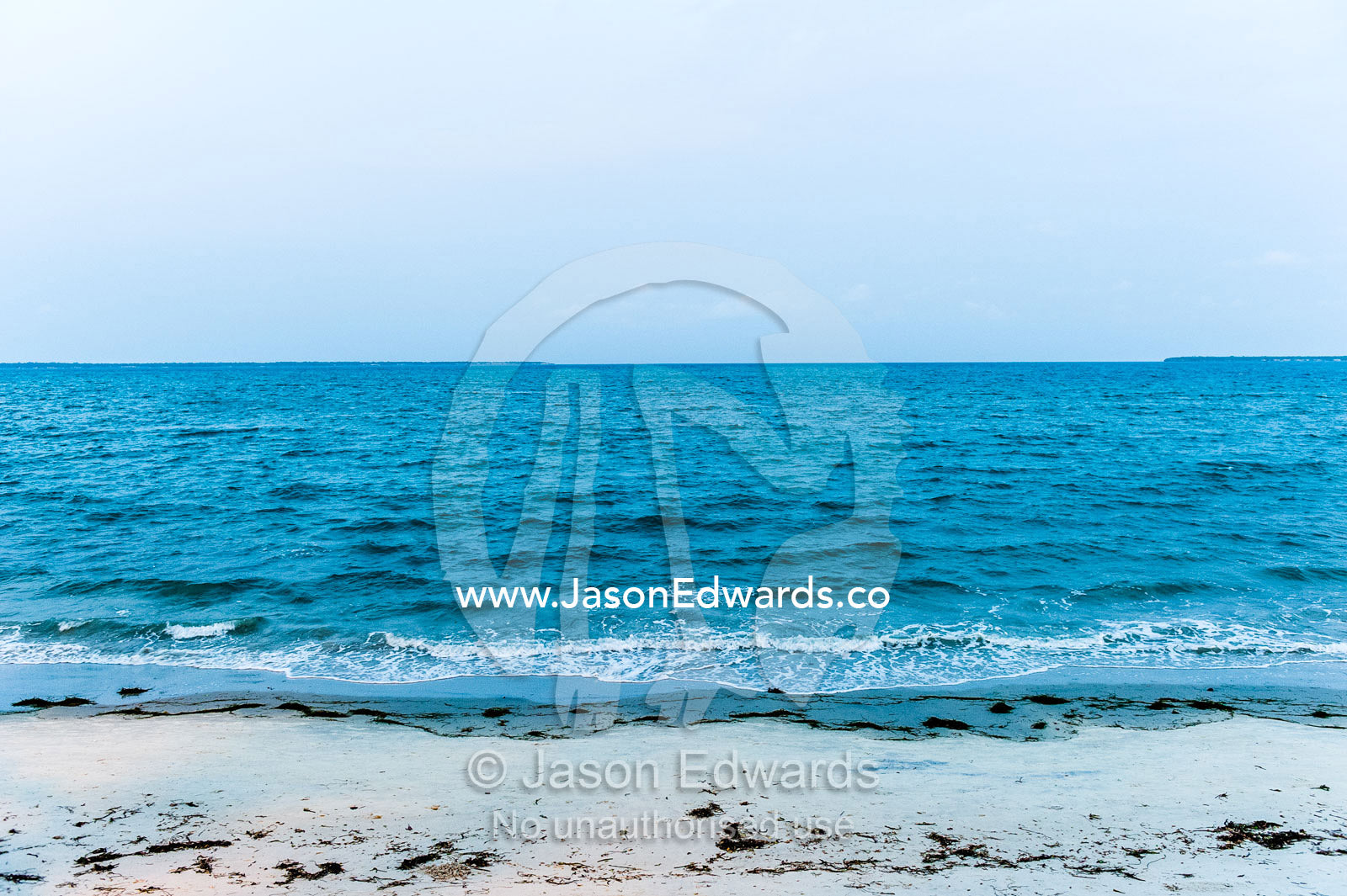 Tropical waves from the ocean lap the sandy shoreline of a bay after sunset. Dar es Salaam, Kawe, Tanzania.