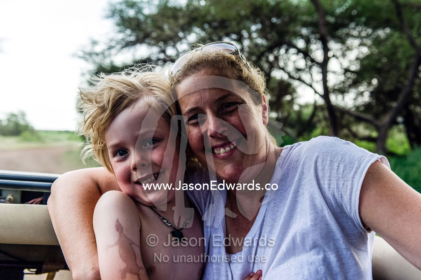 A mother and son ride through the forest in a 4WD whilst on safari in Africa. Lake Manyara National Park, Arusha Region, Tanzania.