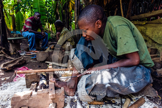 An artist carves a candle stick out of mahogany timber in a village workshop. Mto Wa Mbu, Lake Manyara National Park, Monduli District, Arusha Region, Tanzania, Africa.