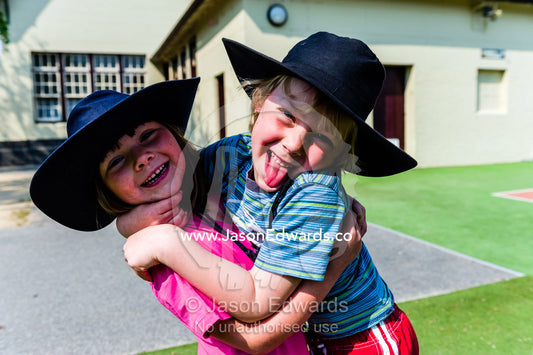 Two friends hug each other in the school play ground on a summers day. Carlton North Primary School, Carlton North, Melbourne, Victoria, Australia.