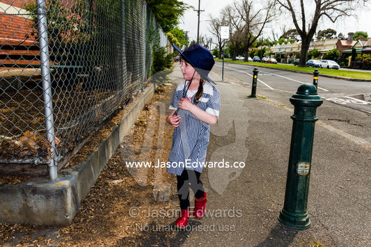 A school girl hot from raising funds in a school walkathon in summer. Carlton North Primary School, Carlton North, Melbourne, Victoria, Australia.