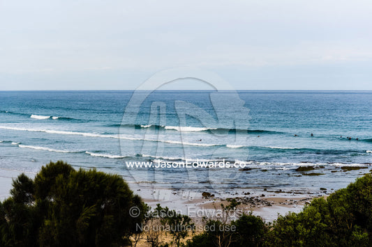 Surfers waiting for winter waves at low tide at a forest surf break. Wye River, Great Ocean Road, Victoria, Australia.