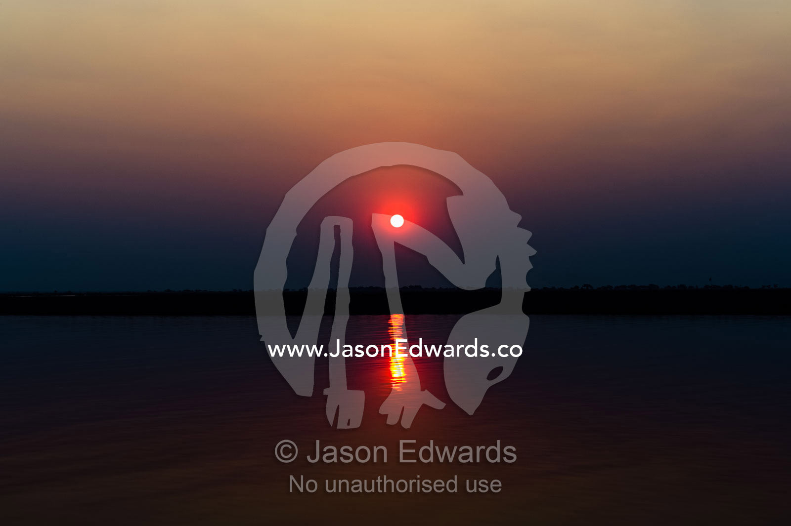 A flaming sunset over a still wetland during the burning season. Chobe River, Chobe National Park, Botswana.