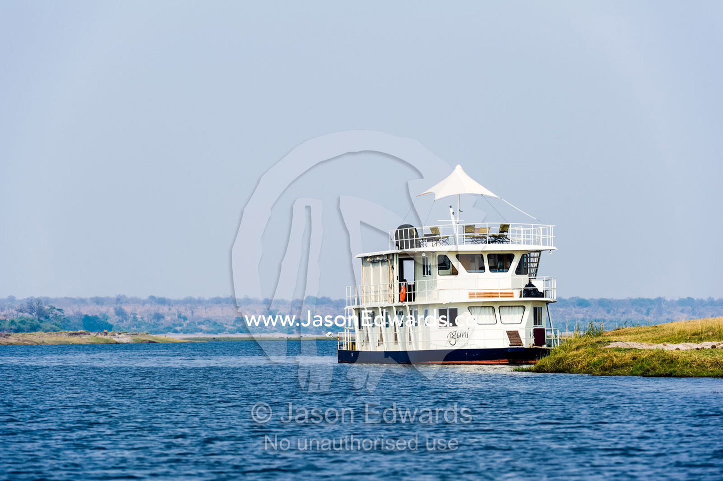 A tourist houseboat moored on the shore of a wetland in a river delta. Chobe River, Chobe National Park, Botswana.