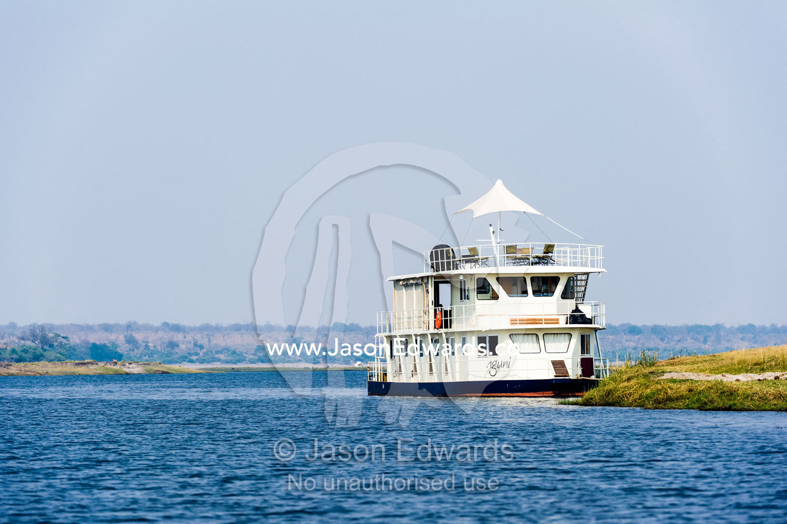 A tourist houseboat moored on the shore of a wetland in a river delta. Chobe River, Chobe National Park, Botswana.
