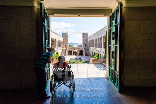 An elderly lady looking over the Memorial Courtyard and Memorial Pool from the Hall of Memory. Australian War Memorial, Canberra, Australian Capital Territory, Australia.