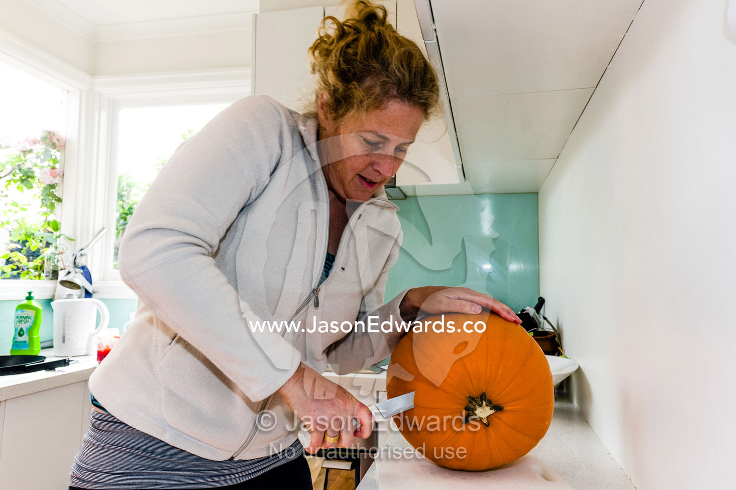 A mother carves a jack-o'-lantern pumpkin for halloween celebrations. Carlton North, Melbourne, Victoria, Australia.