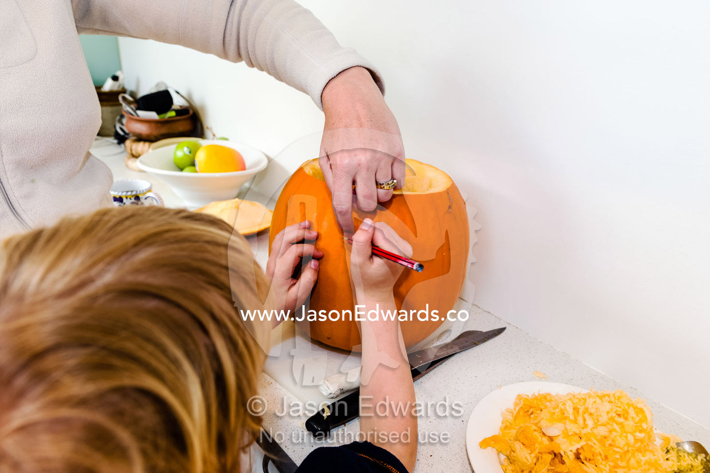 A boy draws a face on a jack-o'-lantern pumpkin for halloween. Carlton North, Melbourne, Victoria, Australia.