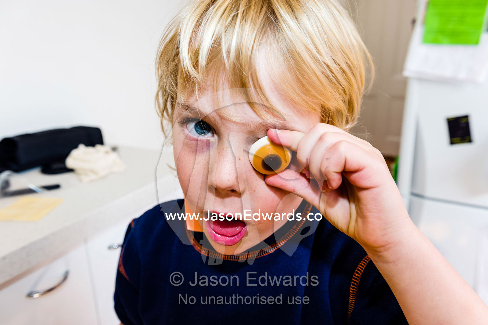 A zombie boy holds a scary candy eyeball to his face at halloween. Carlton North, Melbourne, Victoria, Australia.