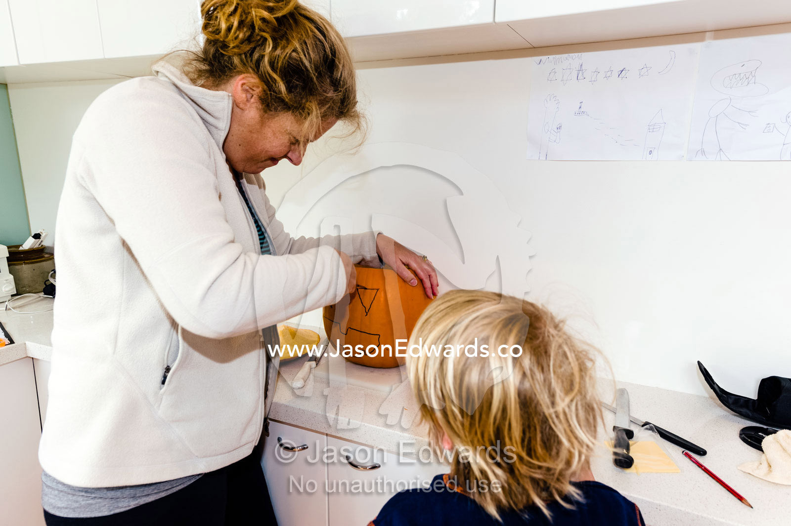 A mother and son carve a jack-o'-lantern pumpkin for halloween. Carlton North, Melbourne, Victoria, Australia.