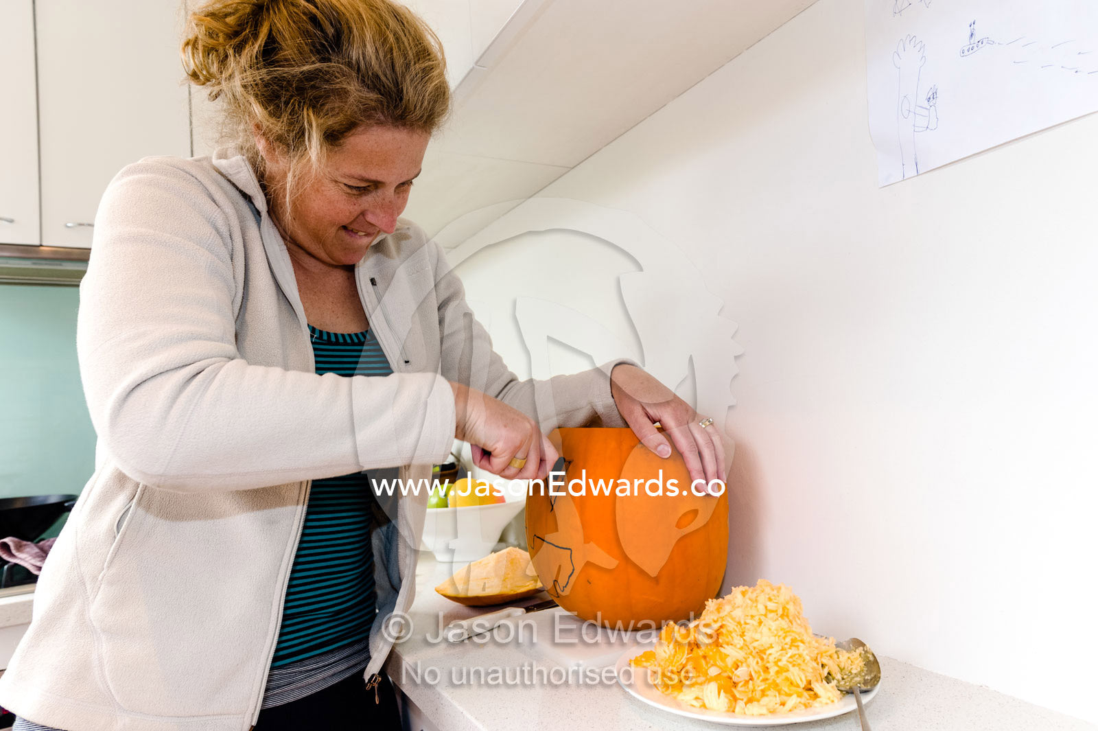 A mother carves a jack-o'-lantern pumpkin for halloween celebrations. Carlton North, Melbourne, Victoria, Australia.