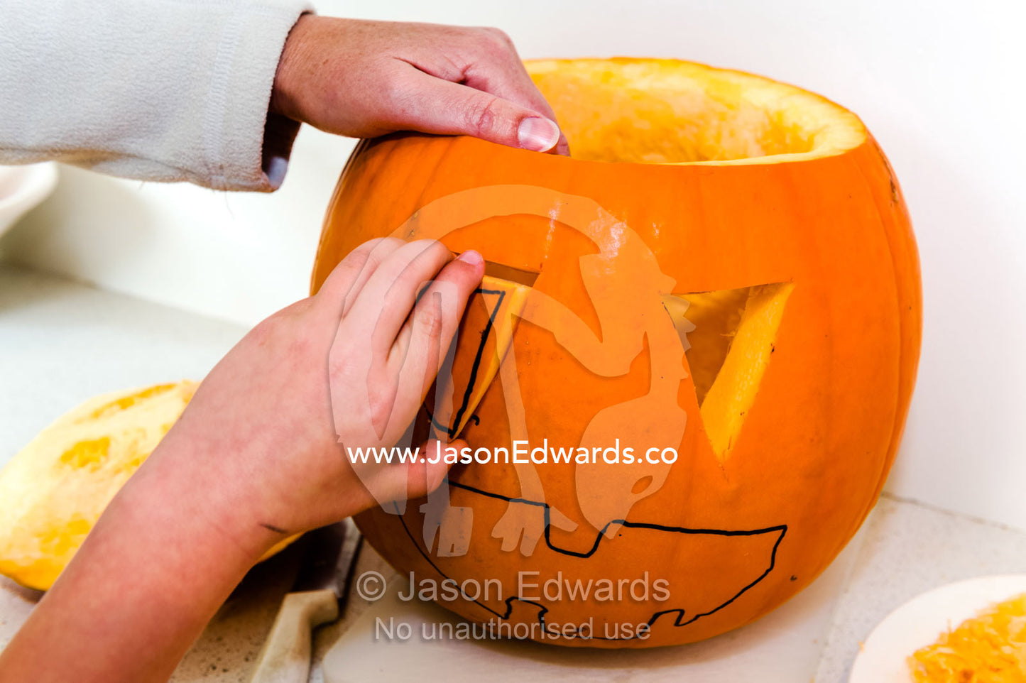 A boy removes an eye from a jack-o'-lantern pumpkin for halloween. Carlton North, Melbourne, Victoria, Australia.