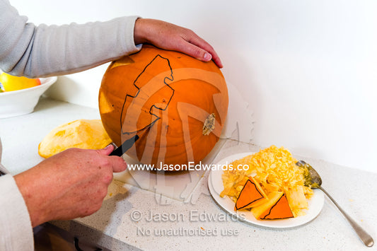 A mother carves a jack-o'-lantern pumpkin for halloween celebrations. Carlton North, Melbourne, Victoria, Australia.