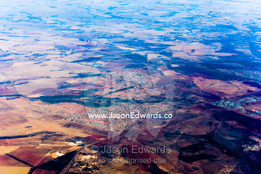 The urban sprawl of a village surrounded by a vast plain dotted with agricultural land and farms. Johannesburg, Gauteng Province, South Africa, Africa.
