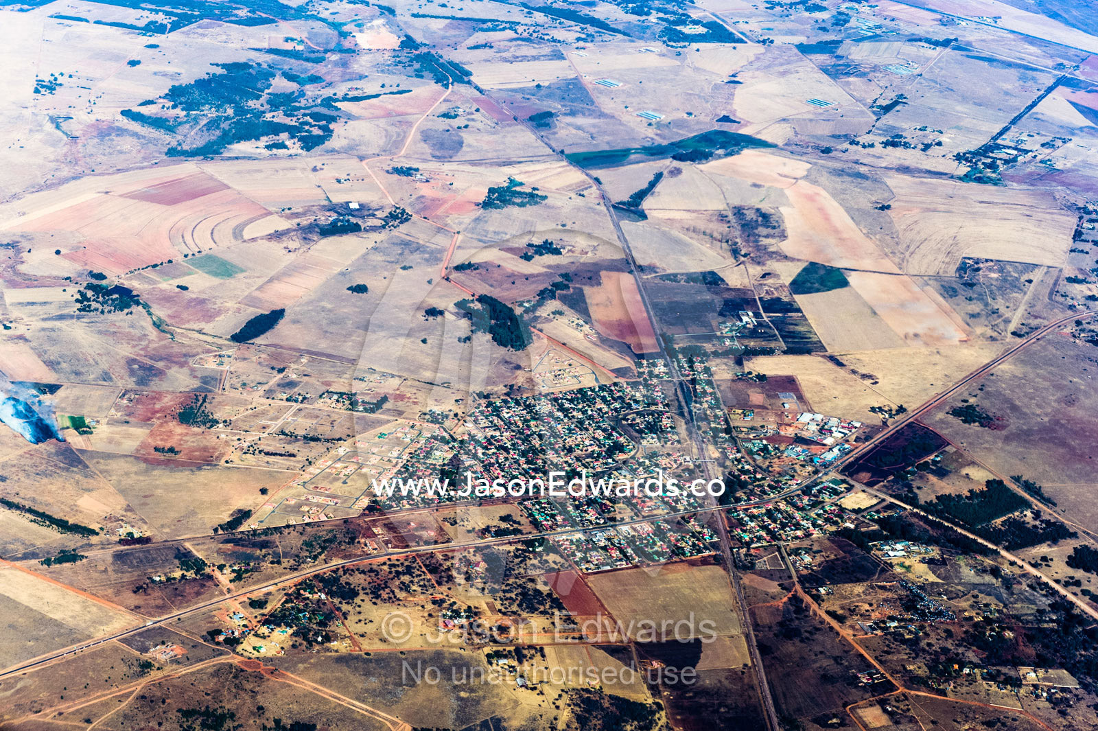 The urban sprawl of a village surrounded by a vast plain dotted with agricultural land and farms. Johannesburg, Gauteng Province, South Africa, Africa.