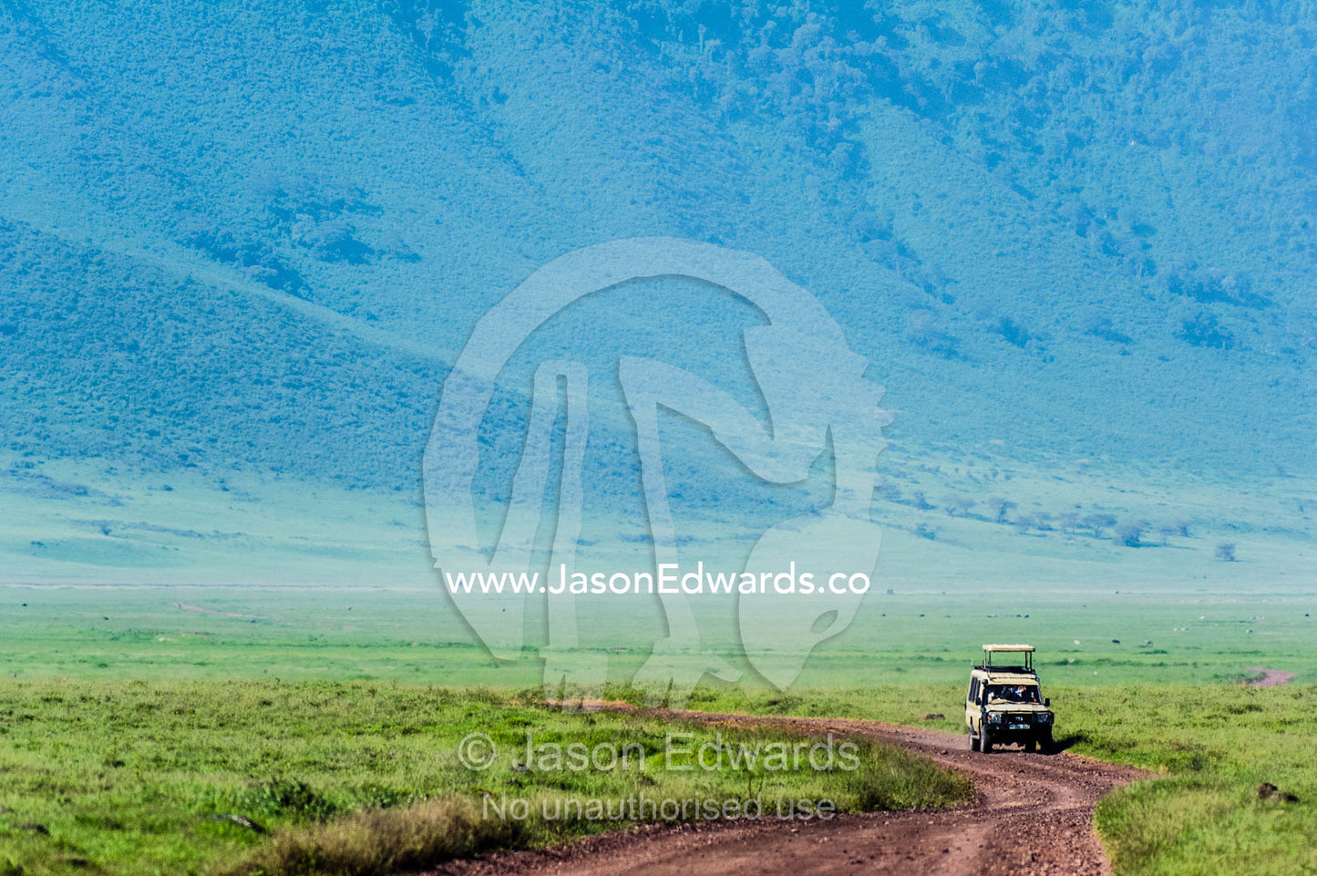 A safari vehicle crosses the savannah plain on the floor of a volcano caldera. Ngorongoro Crater, Ngorongoro Conservation Area, Ngorongoro District, Tanzania.