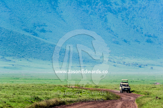 A safari vehicle crosses the savannah plain on the floor of a volcano caldera. Ngorongoro Crater, Ngorongoro Conservation Area, Ngorongoro District, Tanzania.