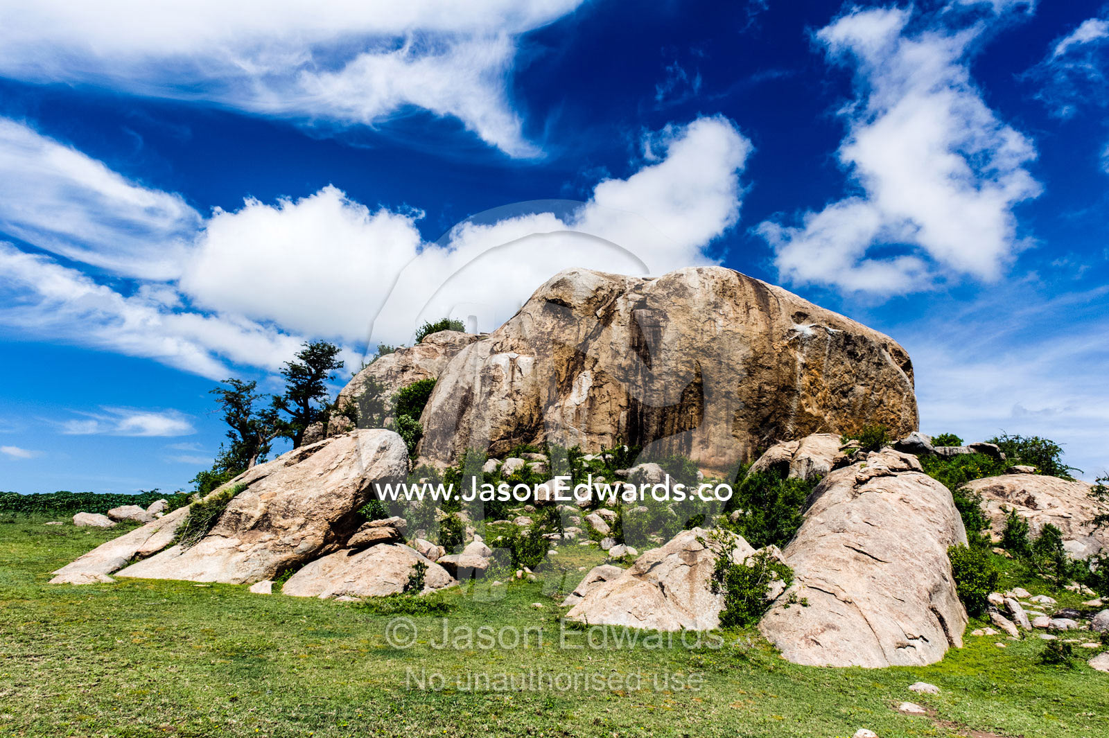 Wispy clouds crowning a rocky granite outcrop on the savannah known as a kopje. Ngorongoro Conservation Area, Ngorongoro District, Tanzania.