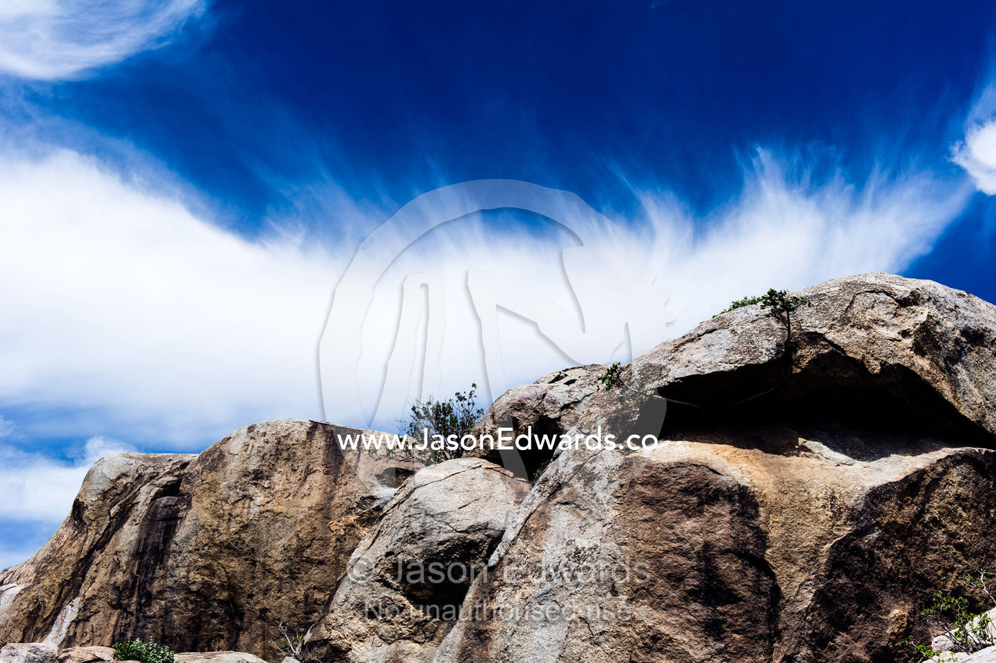 Wispy clouds crowning a rocky granite outcrop on the savannah known as a kopje. Ngorongoro Conservation Area, Ngorongoro District, Tanzania.