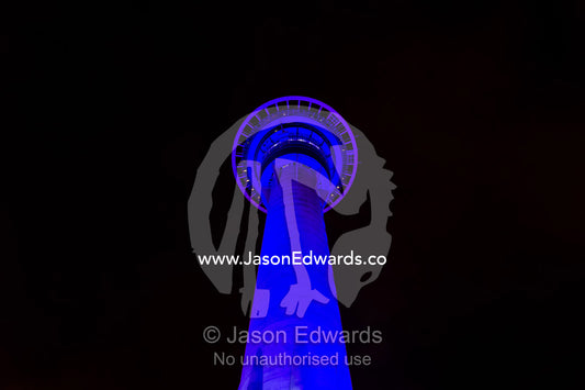 The enormous blue concrete rocket-like Sky Tower rises above Auckland city at night. Sky Tower, Auckland, New Zealand.
