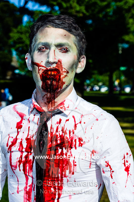 A snarling modern businessman dripping blood dressed as a zombie. Queen Victoria Gardens, Royal Botanic Gardens, South Yarra, Melbourne, Victoria, Australia.