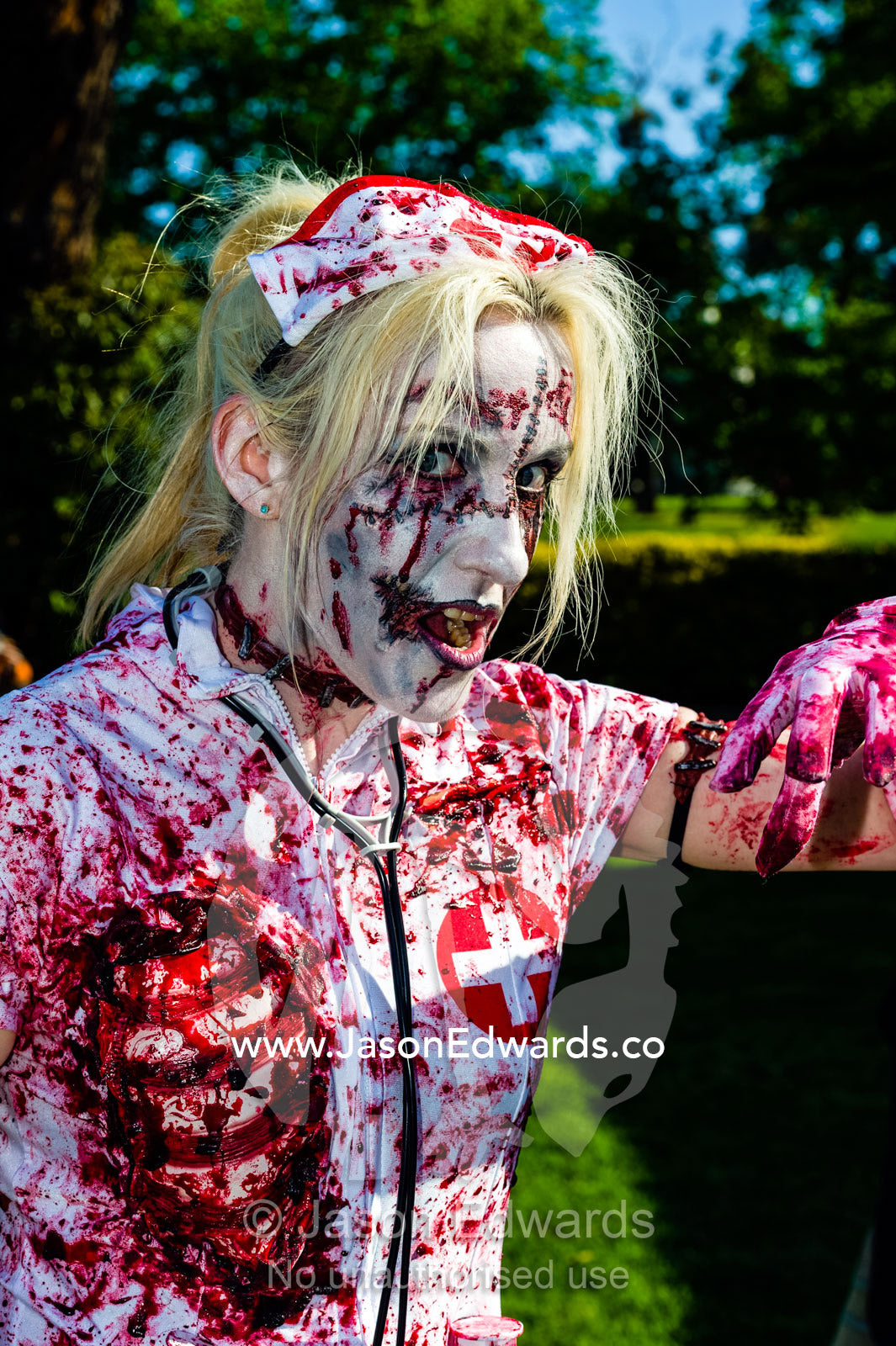 A blood-soaked snarling nurse dripping blood dressed as a zombie. Queen Victoria Gardens, Royal Botanic Gardens, South Yarra, Melbourne, Victoria, Australia.
