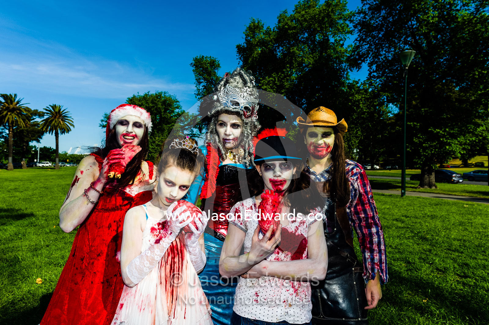 A family dresses as zombies eating fingers and hearts at a festival. Queen Victoria Gardens, Royal Botanic Gardens, South Yarra, Melbourne, Victoria, Australia.