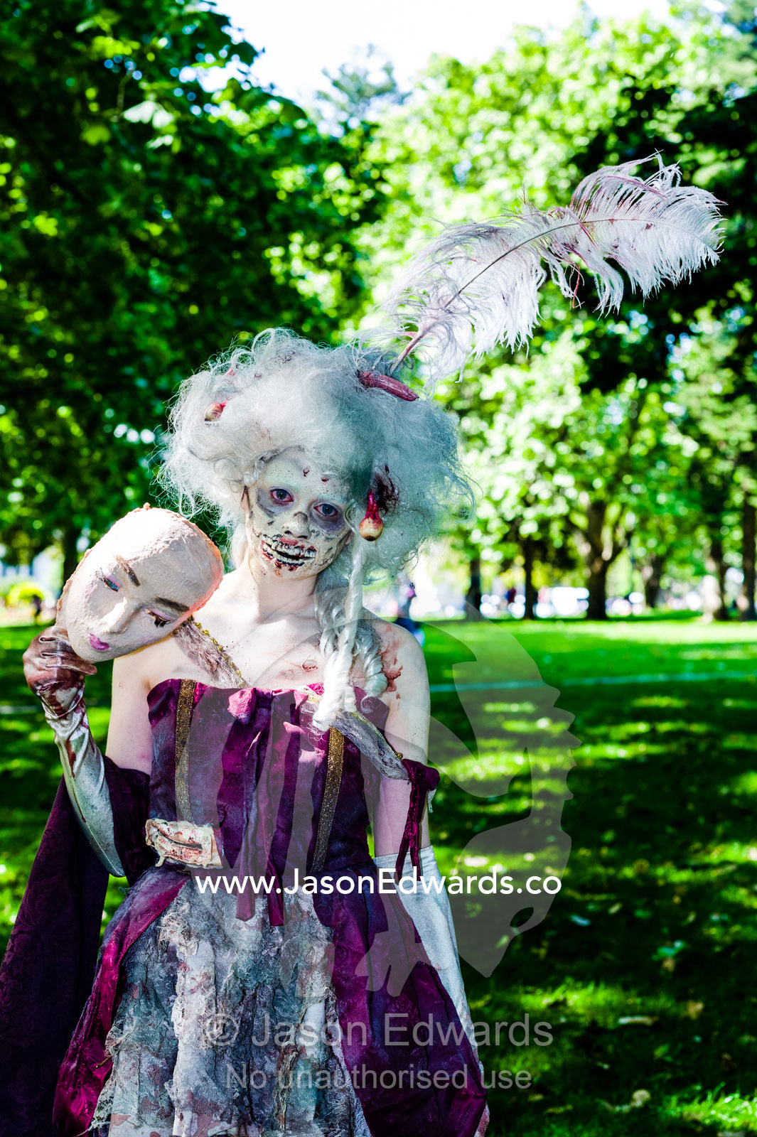 Marie Antoinette with a masquerade mask dressed as a zombie at a festival. Carlton Gardens, World Heritage Site, Carlton, Melbourne, Victoria, Australia.