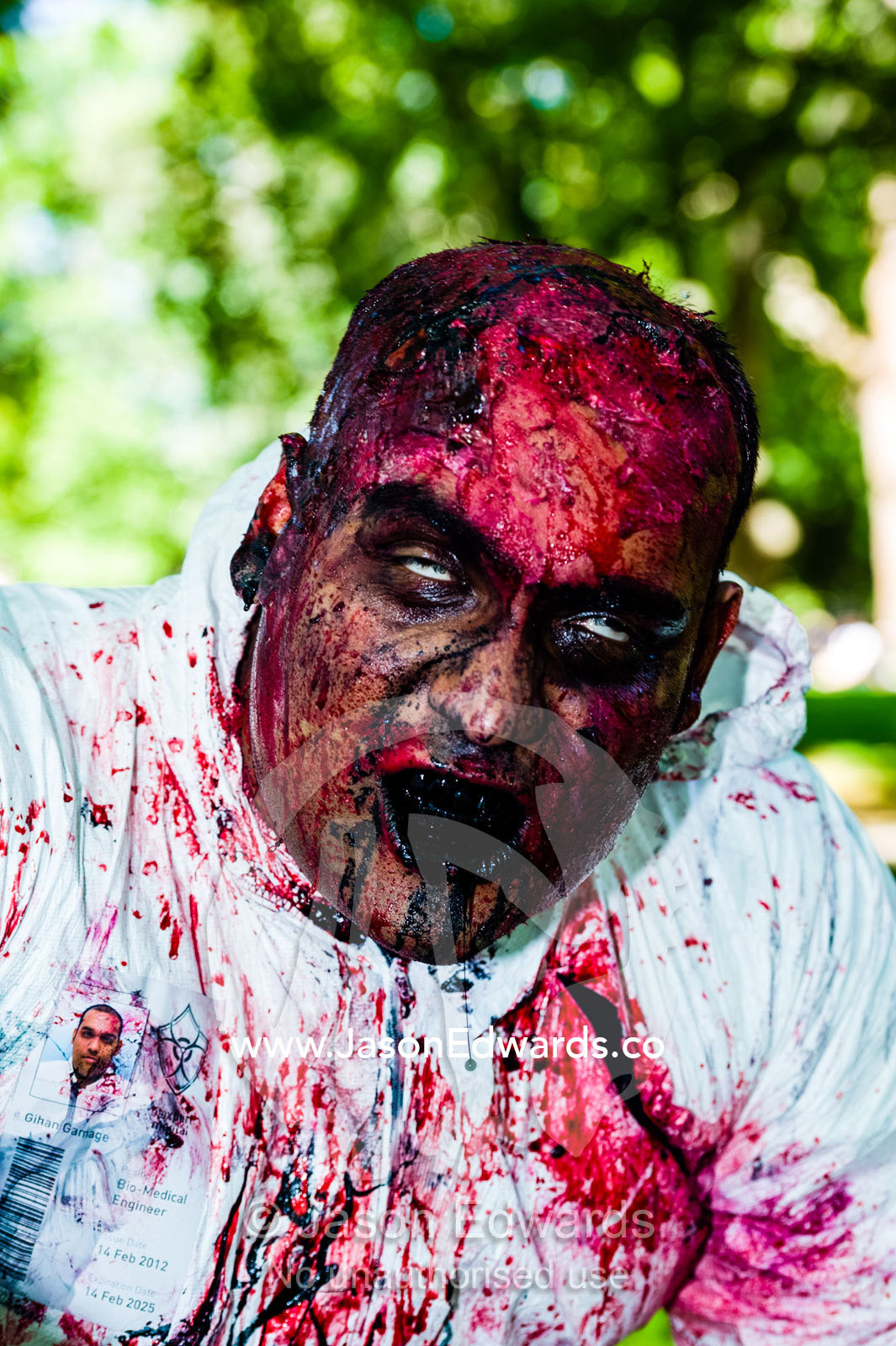 A hospital research technician zombie in a blood-soaked bio hazard suit. Carlton Gardens, World Heritage Site, Carlton, Melbourne, Victoria, Australia.