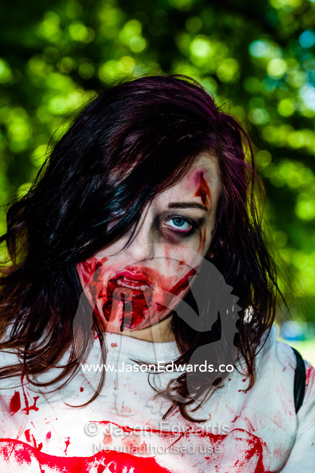 A woman dressed as a drooling zombie at a festival. Carlton Gardens, World Heritage Site, Carlton, Melbourne, Victoria, Australia.