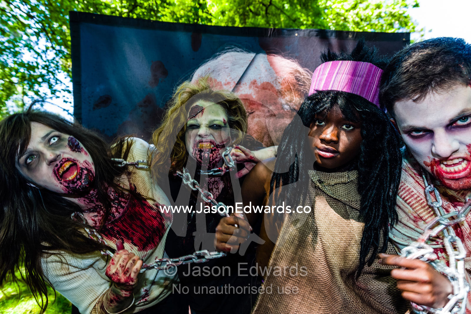 People dressed as zombies held by chains by a character from the Walking Dead. Carlton Gardens, World Heritage Site, Carlton, Melbourne, Victoria, Australia.