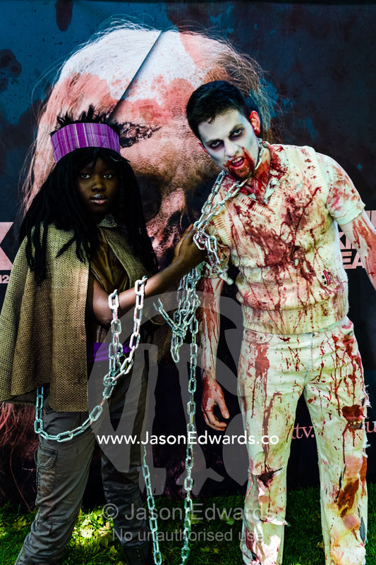 A blood-saoked zombie cricket player restrained by a steel chain by a character from the Walking Dead. Carlton Gardens, World Heritage Site, Carlton, Melbourne, Victoria, Australia.