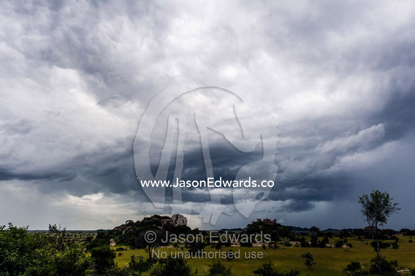 Ominous storm clouds swirl over granite kopjes rising from the savannah grassland. Moru Kopjes, Serengeti National Park, Serengeti, World Heritage Site, Tanzania.