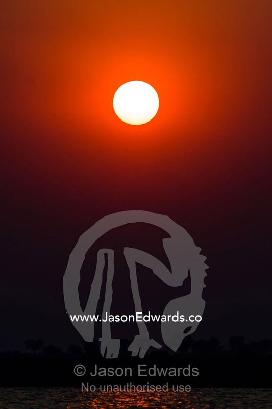 A blazing sunset over the Chobe River coloured by smoke from fires in Zambia. Chobe River, Chobe National Park, Botswana.