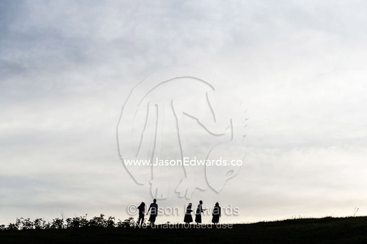 Teenage girls from an orphanage silhouette on the horizon of a farm at sunset. Karatu, Rhotia Valley Lodge, Rhotia Valley, Karatu District, Arusha Region, Tanzania, Africa.