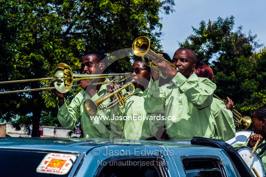 A band plays music for a wedding procession from a utility vehicle in the main street of a village. Mto Wa Mbu, Lake Manyara National Park, Monduli District, Arusha Region, Tanzania, Africa.