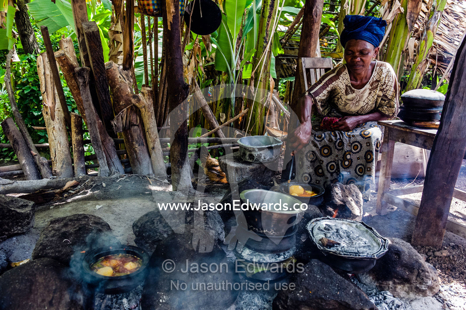 A woman cooks a traditional African meal of potato, meat and vegetables in a village kitchen. Mto Wa Mbu, Lake Manyara National Park, Monduli District, Arusha Region, Tanzania, Africa.