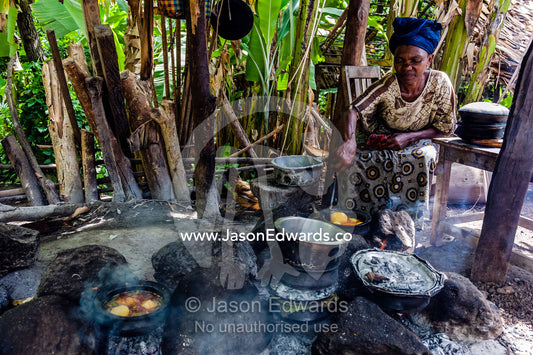 A woman cooks a traditional African meal of potato, meat and vegetables in a village kitchen. Mto Wa Mbu, Lake Manyara National Park, Monduli District, Arusha Region, Tanzania, Africa.