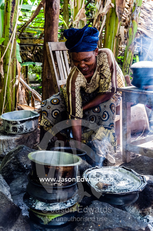 A woman cooking a traditional African meal of potato, meat and vegetables in a village kitchen. Mto Wa Mbu, Lake Manyara National Park, Monduli District, Arusha Region, Tanzania, Africa.