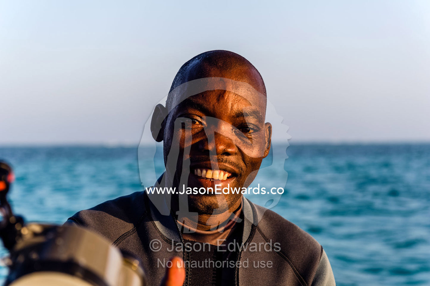 The smiling face of an African scuba diving Master on a boat in the Indian Ocean. Bwejuu, Blue Lagoon Reef, Unguja Island, Zanzibar, Tanzania, Africa.